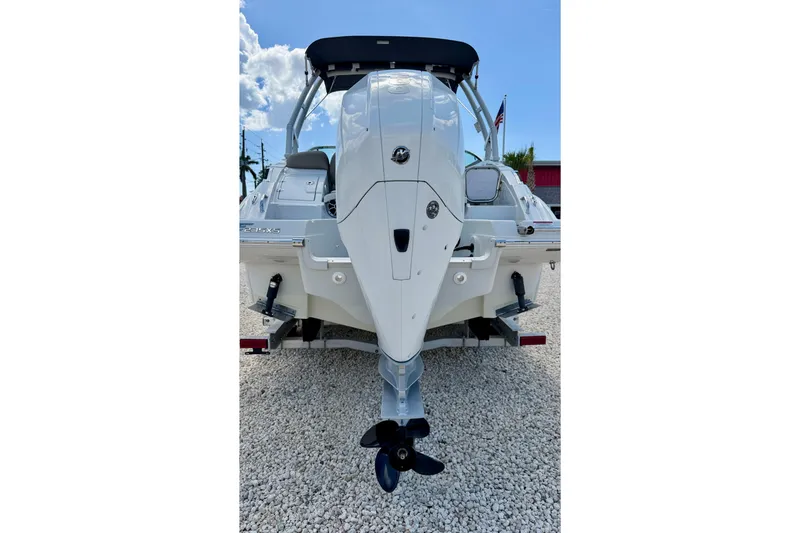 Slide: The Image of 2023 Crownline Eclipse E235 XS boat, rear view, on gravel, showcasing outboard motor. - 37