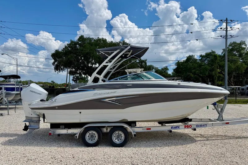 Slide: The Image of 2023 Crownline Eclipse E235 XS boat on trailer, parked outdoors under blue sky. - 4