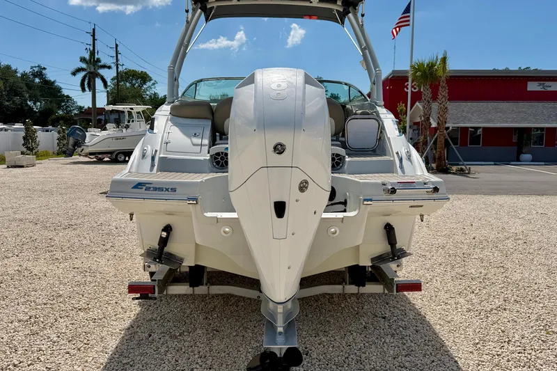 Slide: The Image of 2023 Crownline Eclipse E235 XS boat, rear view, parked on gravel lot with American flag. - 6