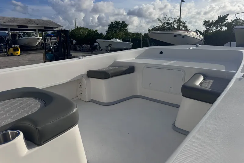 Slide: The Image of 2026 Sundance B22CCR boat interior with cushioned seating, docked under a cloudy sky. - 5