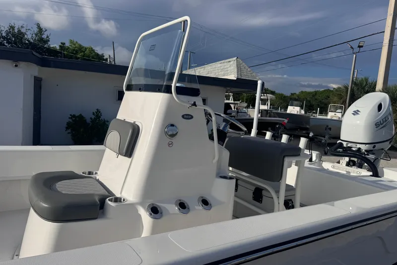 Slide: The Image of 2026 Sundance B22CCR boat with seating and console, parked outdoors under cloudy sky. - 7