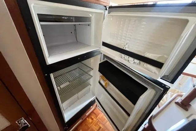 Slide: The Image of Open refrigerator inside a 1989 Carver 3297 Mariner boat, showing empty shelves and compartments. - 18