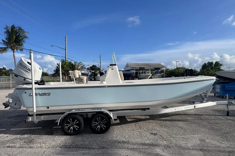 The Image of 2026 Sundance DX22 boat on trailer, featuring Suzuki outboard motor, parked outdoors. - 0