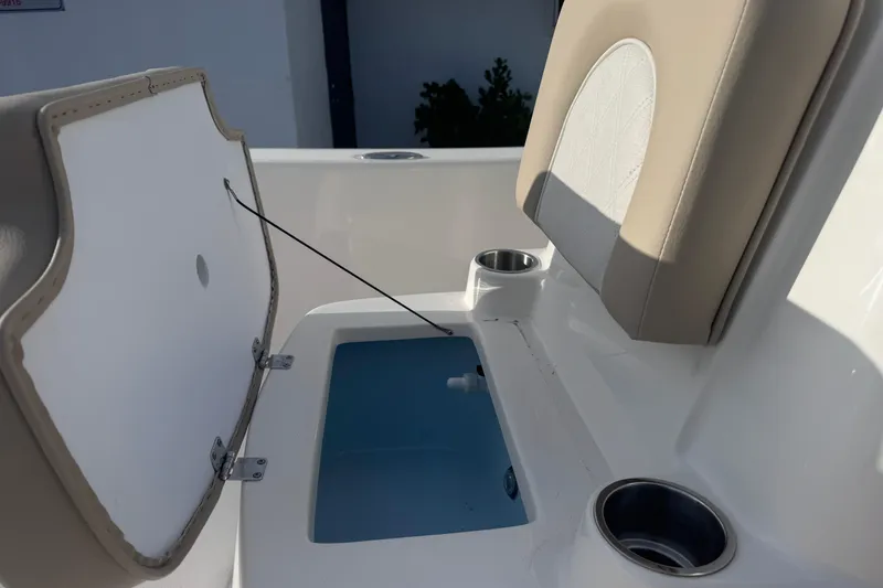 Slide: The Image of 2026 Sundance DX22 boat interior with open storage compartment and cup holders. - 12