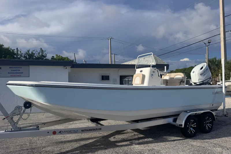 Slide: The Image of 2026 Sundance DX22 boat on trailer, parked outdoors under cloudy sky. - 2