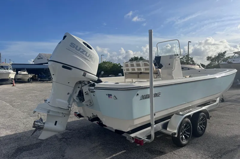 Slide: The Image of 2026 Sundance DX22 boat with Suzuki outboard motor on a trailer in a marina. - 3