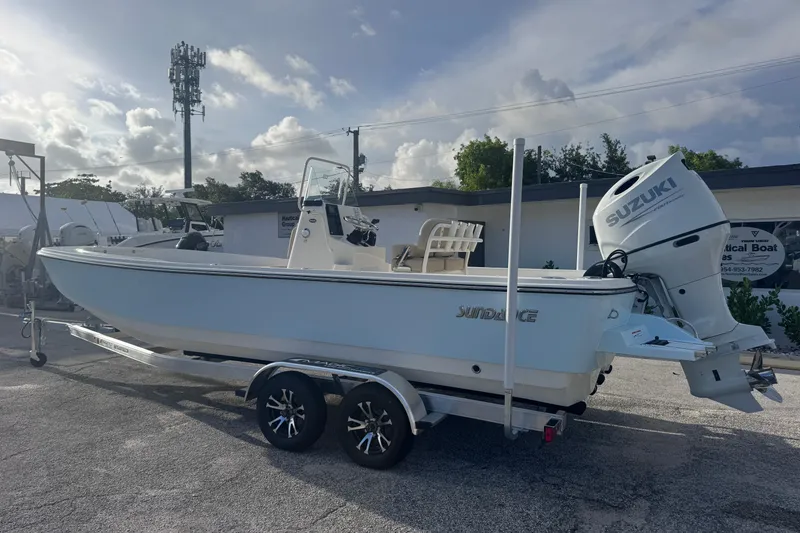 Slide: The Image of 2026 Sundance DX22 boat with Suzuki engine on a trailer, parked outdoors. - 4