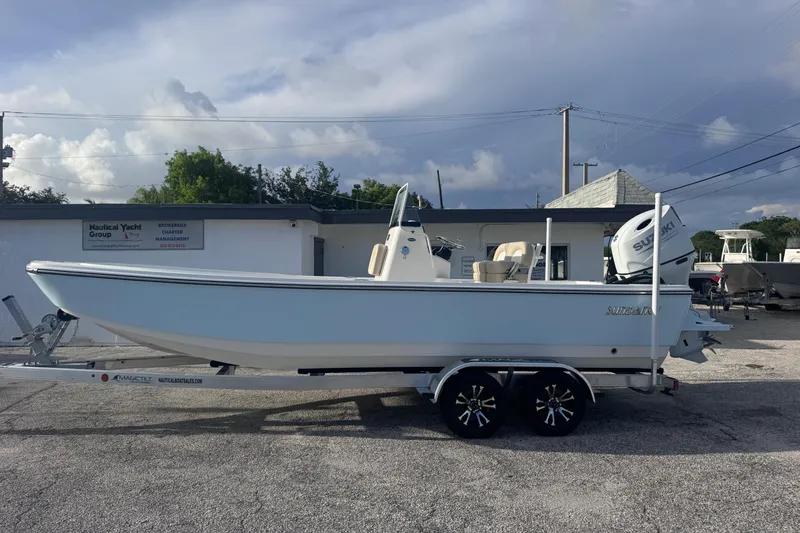 Slide: The Image of 2026 Sundance DX22 boat on trailer, parked outside Nautical Yacht Group building. - 5