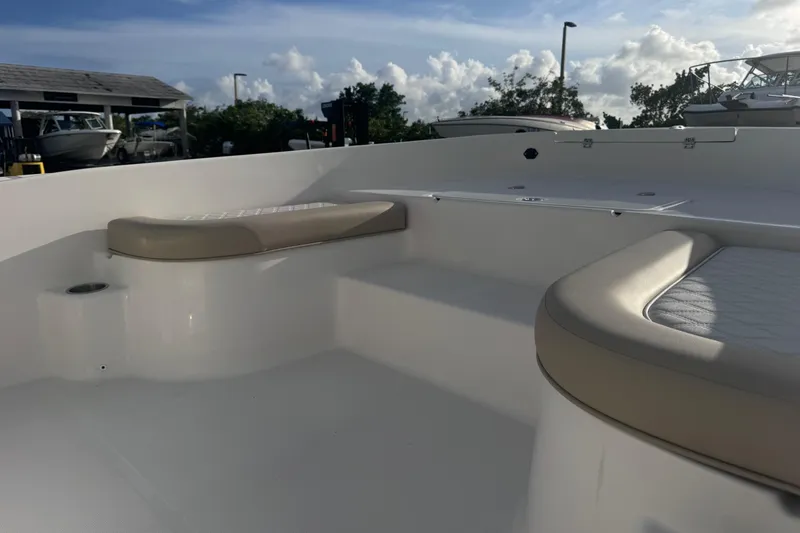 Slide: The Image of 2026 Sundance DX22 boat interior with cushioned seating, docked under a partly cloudy sky. - 6
