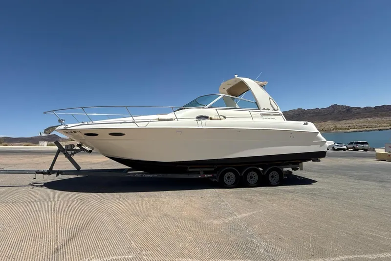 The Image of 1999 Sea Ray Sundancer 310 boat on trailer under clear blue sky. - 0