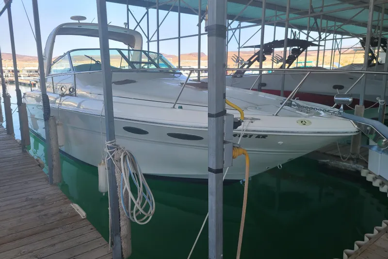 Slide: The Image of 1999 Sea Ray Sundancer 310 docked in a marina, under a covered structure. - 1