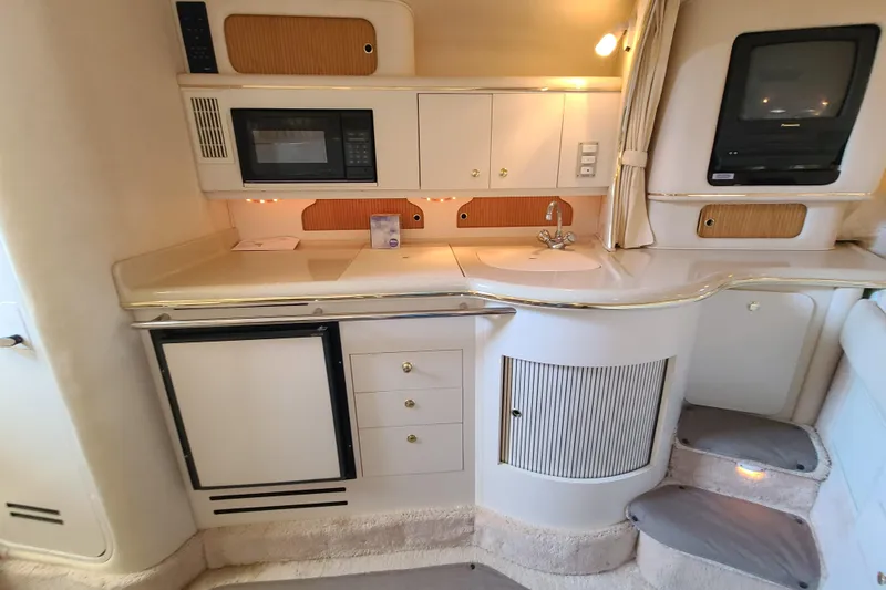 Slide: The Image of Interior of a 1999 Sea Ray Sundancer 310 yacht, featuring a compact kitchenette. - 11