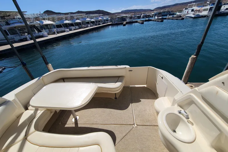 Slide: The Image of 1999 Sea Ray Sundancer 310 boat interior with seating and table, docked at marina. - 19