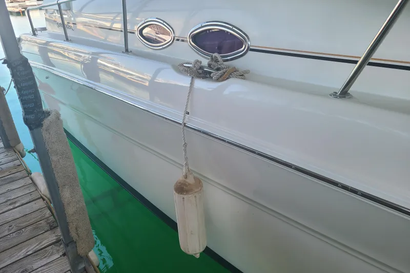 Slide: The Image of 1999 Sea Ray Sundancer 310 docked, showing sleek white hull and fender. - 5