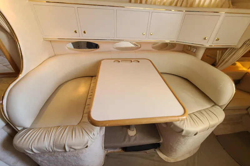Slide: The Image of Interior of a 1999 Sea Ray Sundancer 310, featuring a cozy dining area with white seating. - 9