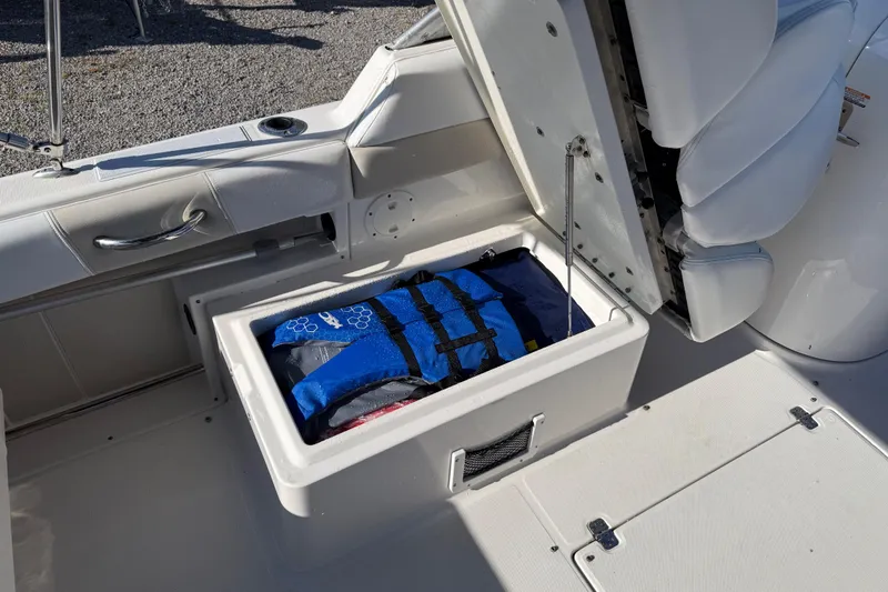 Slide: The Image of 2015 Robalo R227 Dual Console boat storage compartment with life jacket inside. - 19