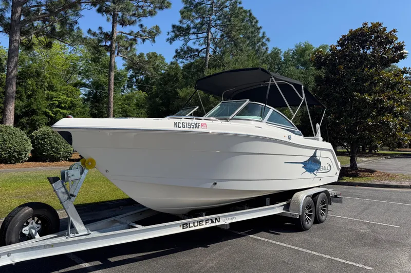 Slide: The Image of 2015 Robalo R227 Dual Console boat on trailer, parked outdoors. - 2