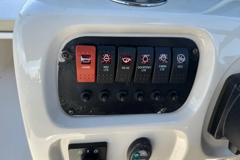Slide: The Image of Control panel of a 2015 Robalo R227 Dual Console boat with labeled switches. - 28