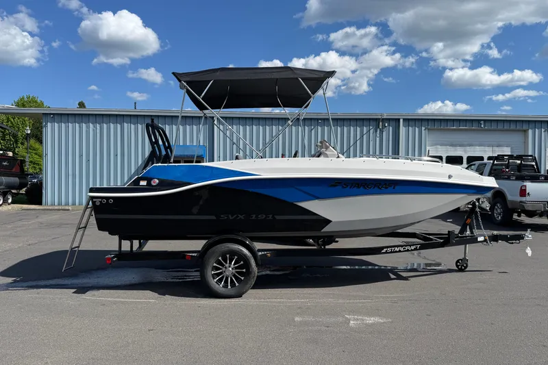 Slide: The Image of 2026 Starcraft SVX 191 OB boat on trailer, parked outdoors under a blue sky. - 4