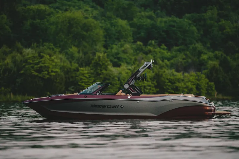 Slide: The Image of Manufacturer Provided Image: 2022 MasterCraft X26 boat on a serene lake with lush green forest background. - 4