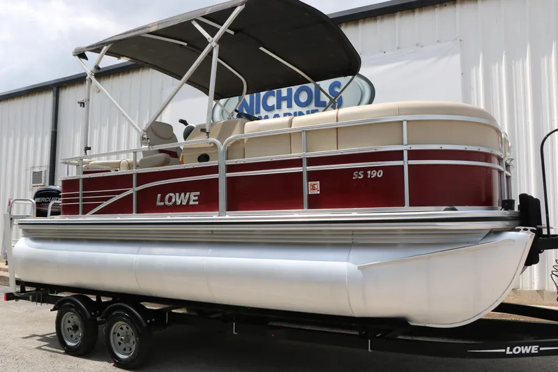 The Image of 2016 Lowe SS 190 pontoon boat on trailer, red and beige design, parked outside. - 1