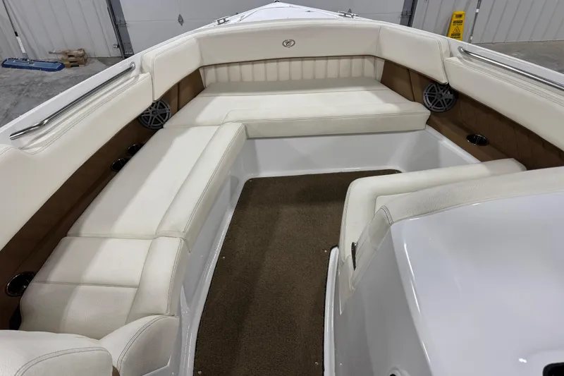 Slide: The Image of 2018 Cobalt boat interior with white seating and brown accents in a garage setting. - 16