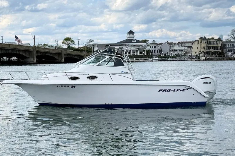 The Image of 2001 Pro-Line 260 Walkaround boat on water, with Yamaha engine, near bridge and houses. - 1
