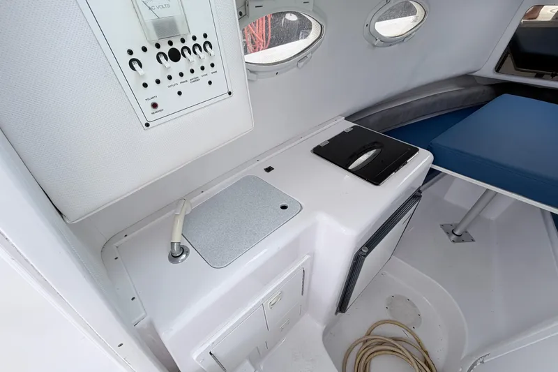 Slide: The Image of Interior of a 2001 Pro-Line 260 Walkaround boat, featuring a compact kitchenette and seating area. - 11