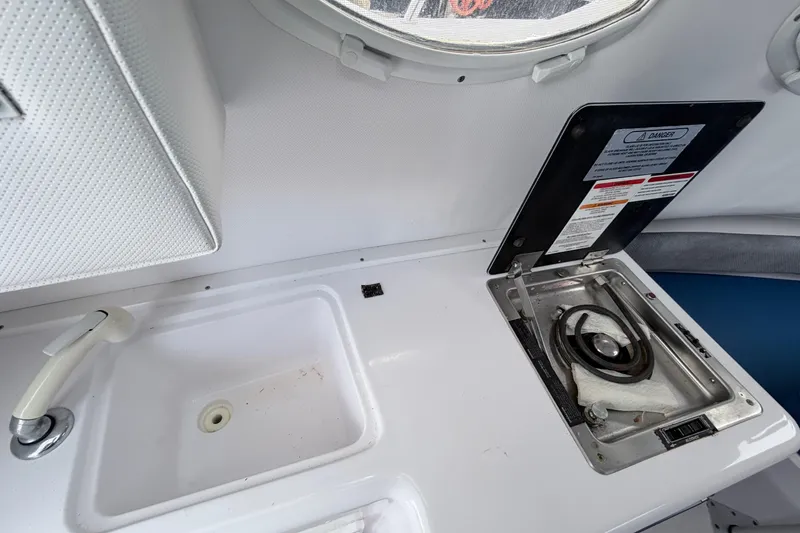 Slide: The Image of 2001 Pro-Line 260 Walkaround boat interior with sink and stove setup. - 12