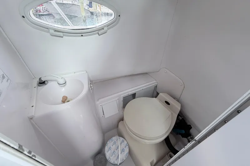 Slide: The Image of Compact bathroom in a 2001 Pro-Line 260 Walkaround boat, featuring a toilet and sink. - 13