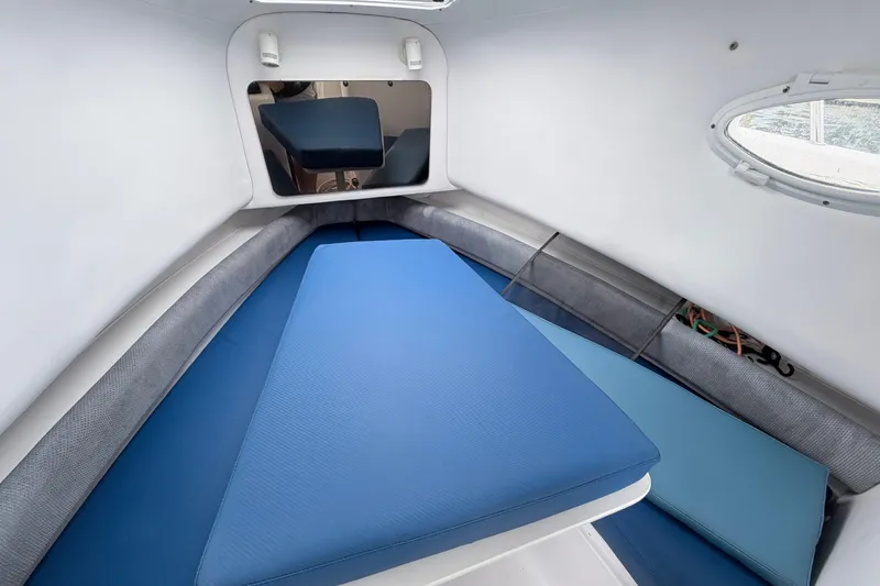 Slide: The Image of Interior cabin of 2001 Pro-Line 260 Walkaround boat with blue cushions and porthole. - 14