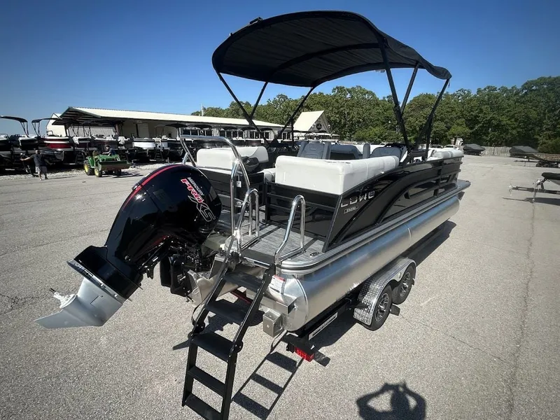 Slide: The Image of 2024 Lowe SS230 WV pontoon boat with black canopy and outboard motor. - 2