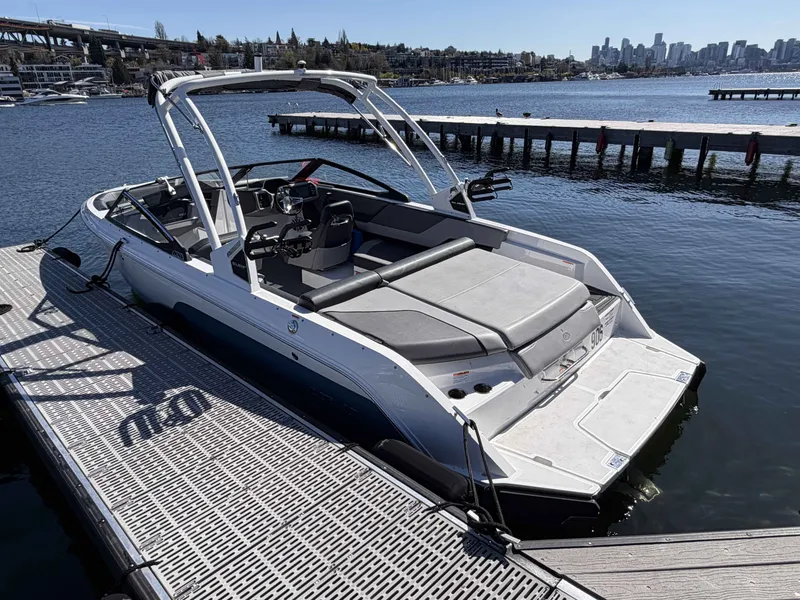 Slide: The Image of 2025 Cobalt CS23 Surf boat docked with city skyline view. - 6