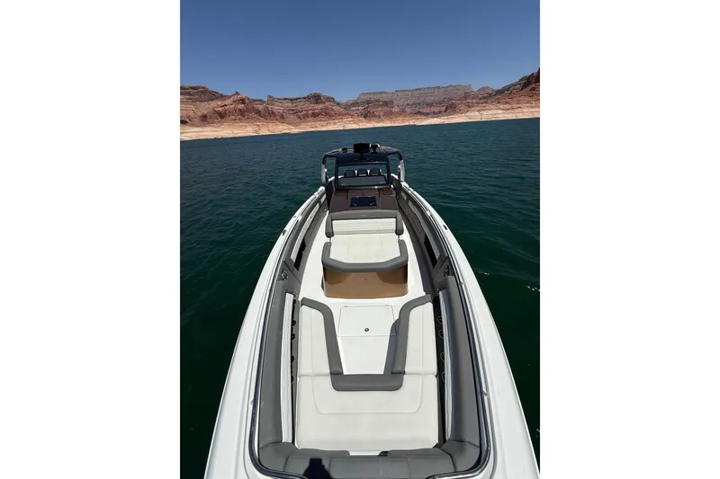 Slide: The Image of 2024 Cigarette 42' Auroris boat on a serene lake with rocky shoreline. - 46
