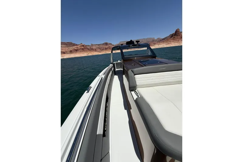 Slide: The Image of 2024 Cigarette 42' Auroris boat cruising on a scenic lake with rocky shoreline. - 48