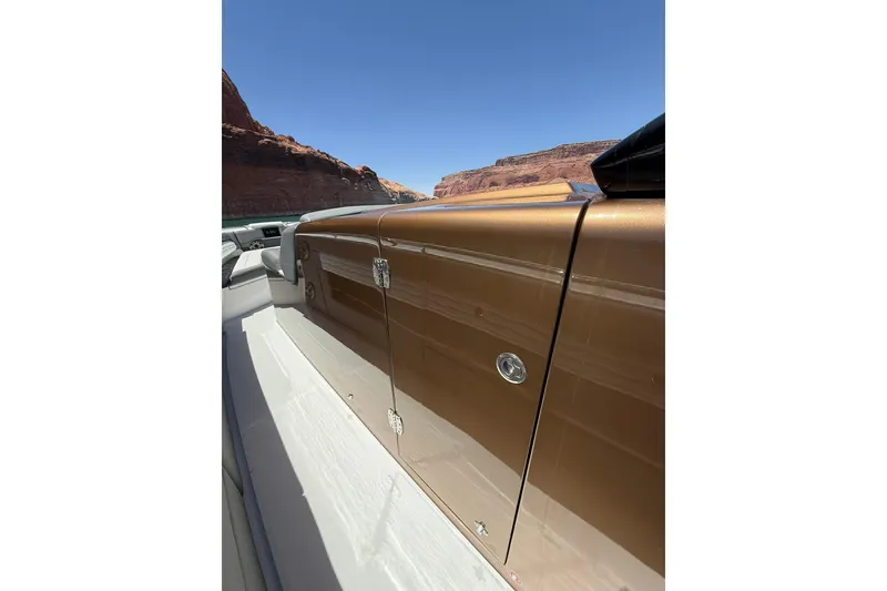 Slide: The Image of 2024 Cigarette 42' Auroris boat with sleek brown exterior, set against canyon backdrop. - 56