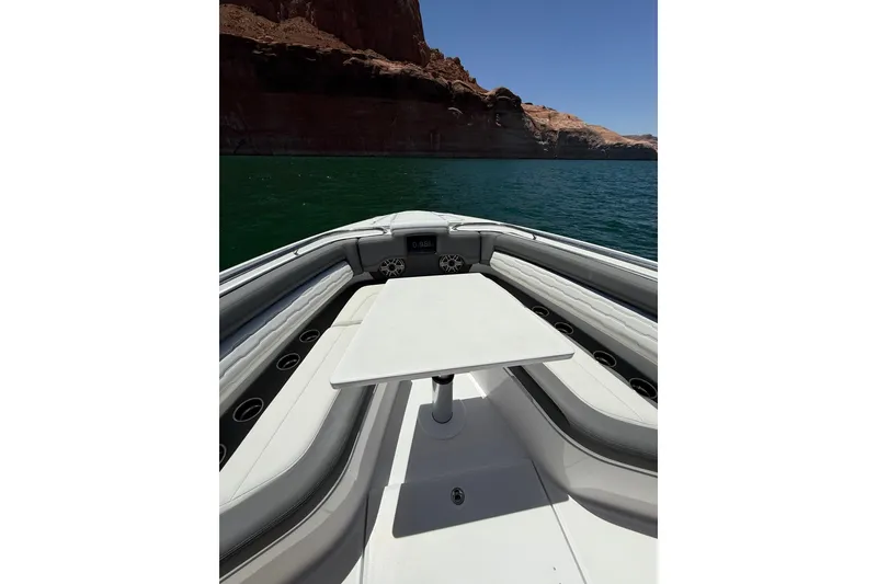 Slide: The Image of 2024 Cigarette 42' Auroris boat interior with table, surrounded by scenic water and cliffs. - 66