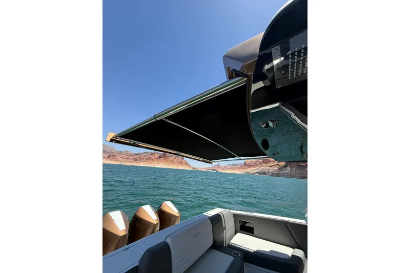 Slide: The Image of 2024 Cigarette 42' Auroris boat with awning, scenic lake view, and rocky shoreline. - 68