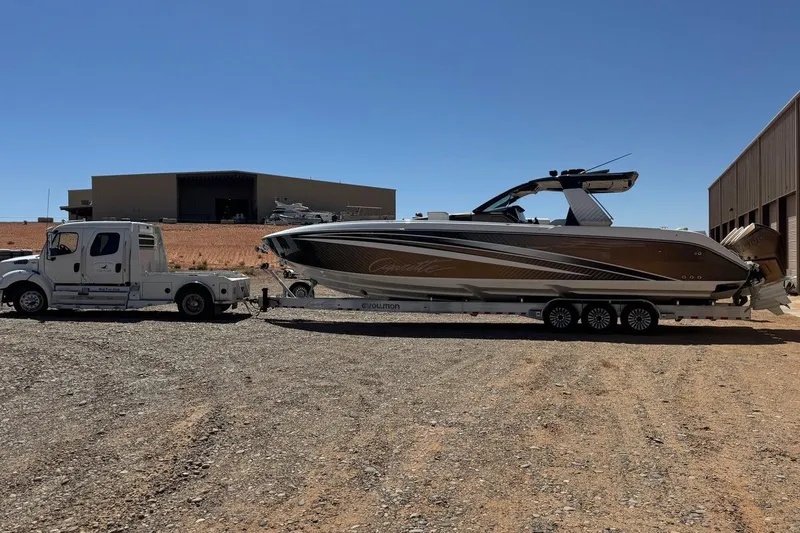 Slide: The Image of 2024 Cigarette 42' Auroris boat on trailer, parked beside a large truck. - 9