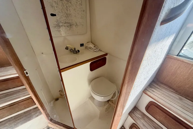 Slide: The Image of 2000 Contender 35 Side Console boat bathroom with sink, toilet, and wooden accents. - 10