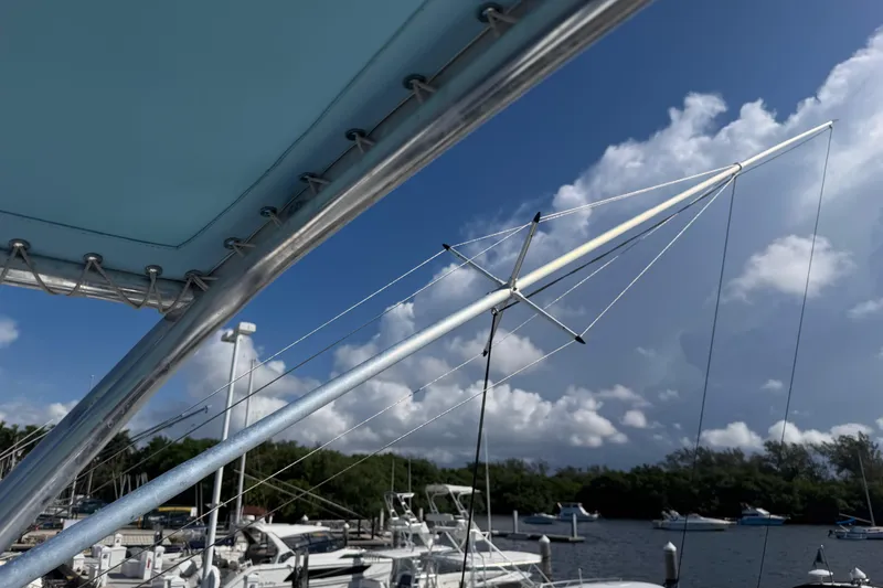 Slide: The Image of Contender 35 Side Console 2000 boat with blue canopy and marina backdrop under cloudy sky. - 18