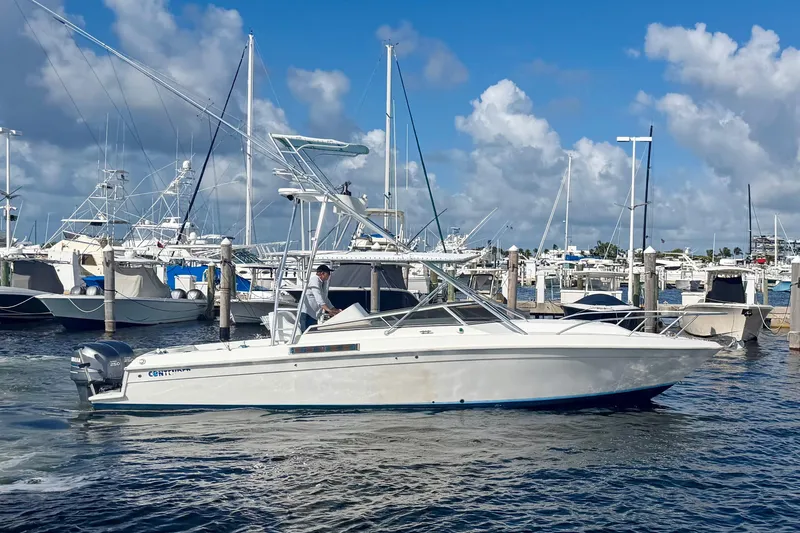 Slide: The Image of 2000 Contender 35 Side Console boat docked in a marina under a blue sky. - 2