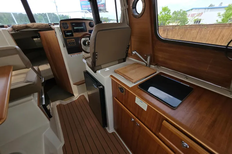 Slide: The Image of Interior of 2021 Ranger Tugs R-23 boat, featuring helm, kitchenette, and wood finishes. - 13