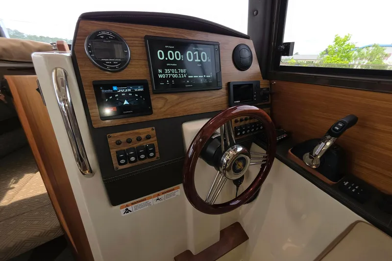 Slide: The Image of 2021 Ranger Tugs R-23 helm with GPS display, wooden steering wheel, and control panel. - 9