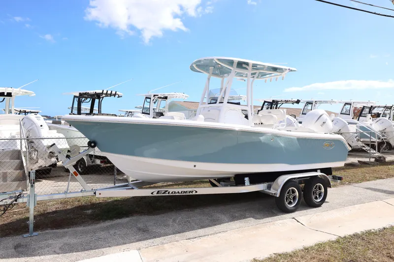 Slide: The Image of 2026 Sea Hunt Ultra 219 boat on trailer under clear blue sky. - 15