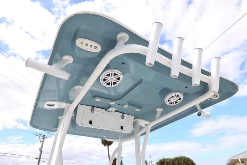 Slide: The Image of T-top of 2026 Sea Hunt Ultra 219 boat with rod holders and speakers against a cloudy sky. - 6