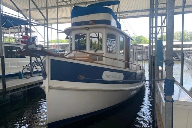 Slide: The Image of 1986 Pilgrim 40 boat docked in a covered marina, featuring a blue and white exterior. - 1