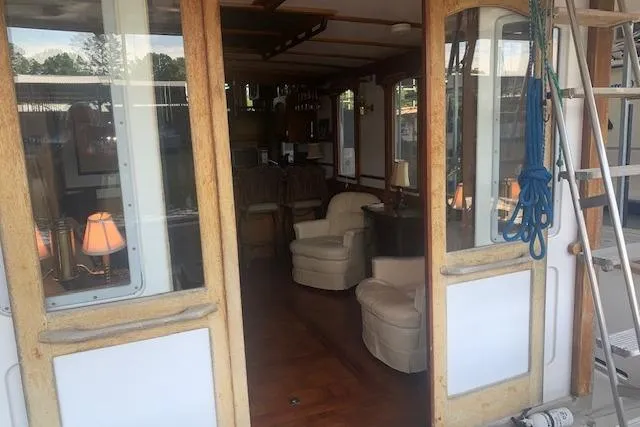Slide: The Image of Interior view of a 1986 Pilgrim 40 boat, featuring cozy seating and wooden accents. - 17