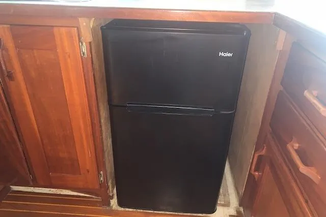 Slide: The Image of Black Haier mini fridge in wooden kitchen cabinetry, Pilgrim 40, 1986 model. - 25