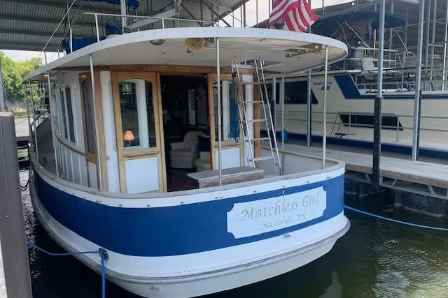 Slide: The Image of 1986 Pilgrim 40 houseboat named "Matchless Girl" docked in a marina. - 3